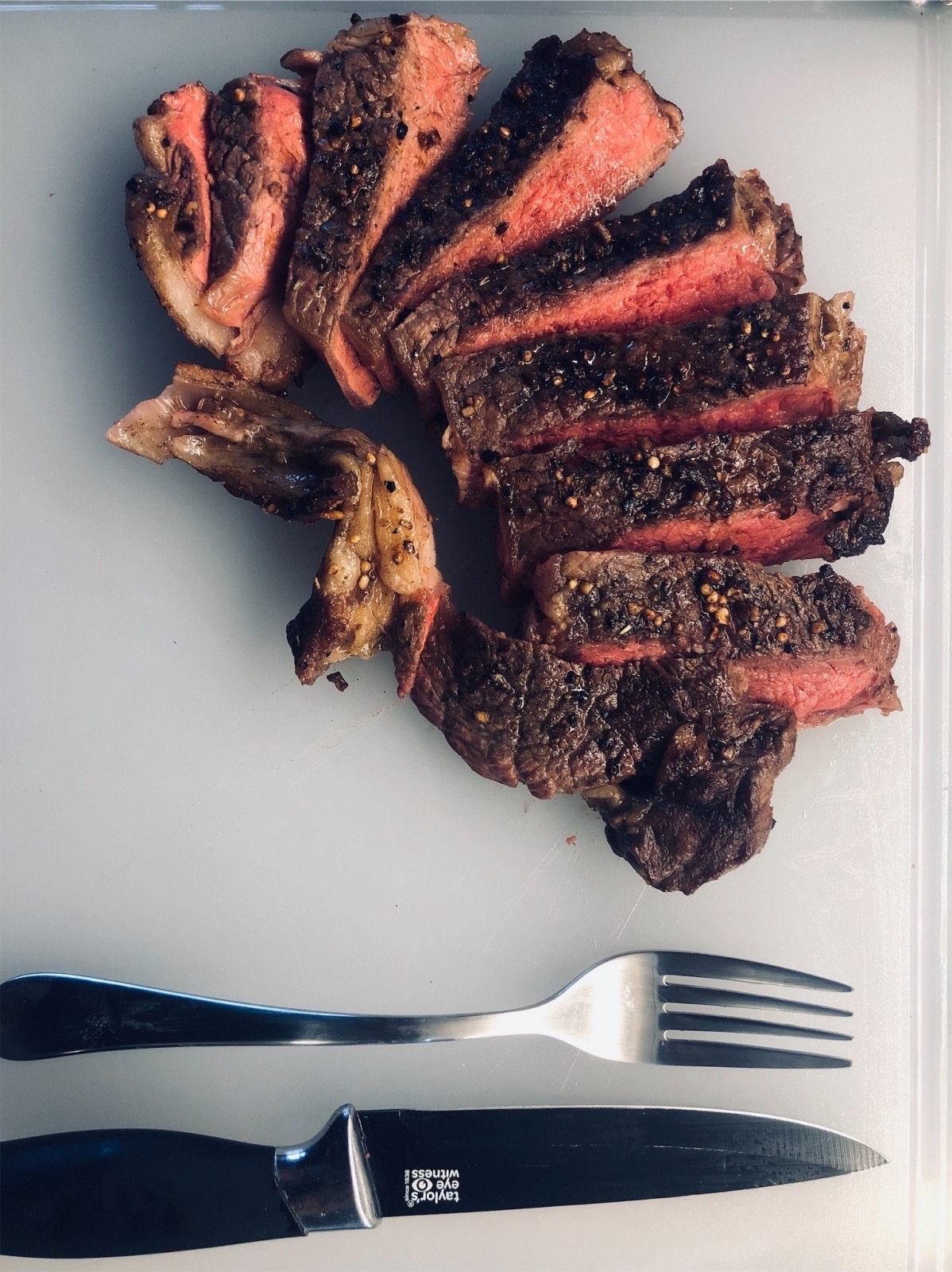 picture of a steak and utensils on a cutting board