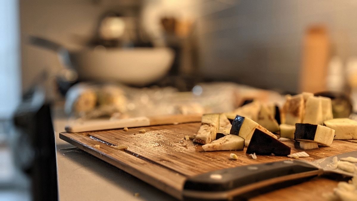 a picture of a cutting board and a knife with some eggplants chopped up